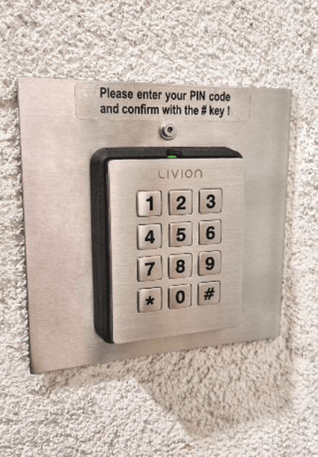 Nummerncodeschloss an der Wand Nummerncodeschloss für PIN-Eingabe mit Edelstahlrahmen an einer weißen Wand montiert