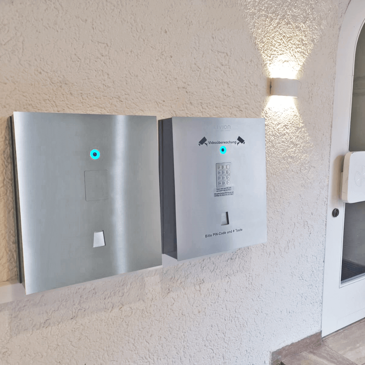 Elektronische Zutrittskontrolle mit PIN-Code-Tastatur und moderner Zugangstechnologie Zwei silberne Zutrittskontrollsysteme an einer Wand, eines mit PIN-Code-Tastatur und Videoüberwachung, ideal für sichere Gebäudezugänge