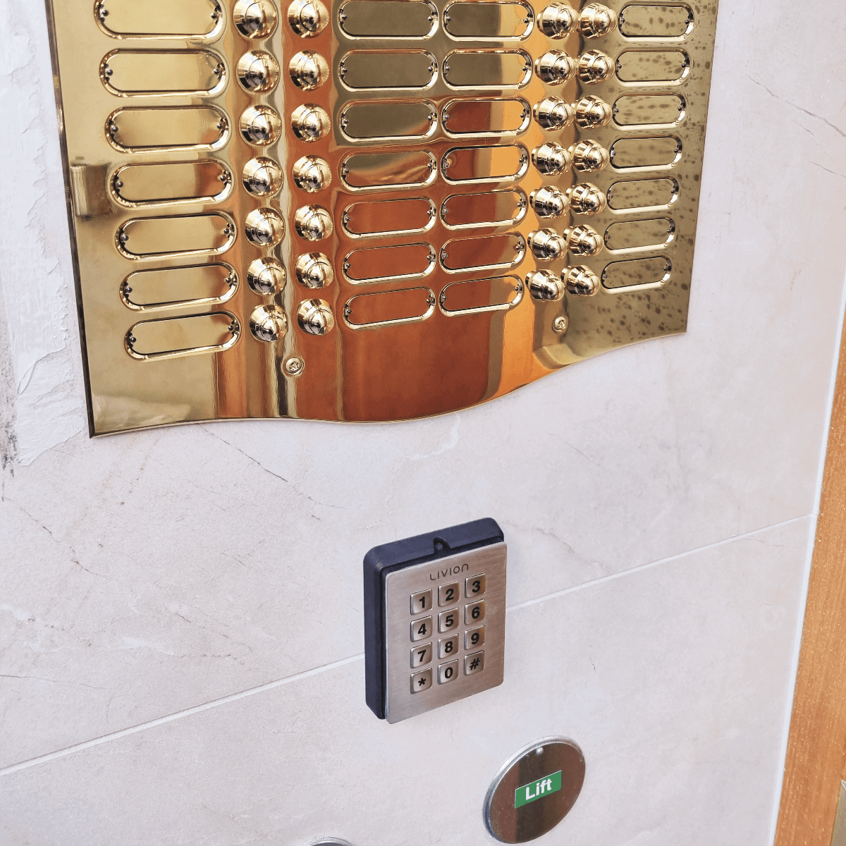 Moderne Gegensprechanlage mit vergoldeter Klingelplatte, Zahlenfeld und Aufzugsknopf Detailaufnahme einer modernen Gegensprechanlage mit goldener Klingelplatte, Zahlentastatur und grünem Aufzugsknopf
