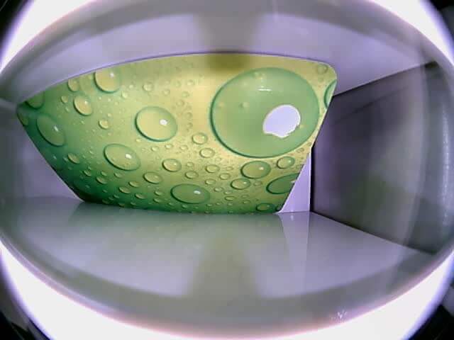 Grüne Kunststoffplatte mit Tropfenmuster, eingesetzt in einen weißen Behälter Grüne Platte mit Wasserblasen-Optik in einem weißen rechteckigen Behälter von oben betrachtet