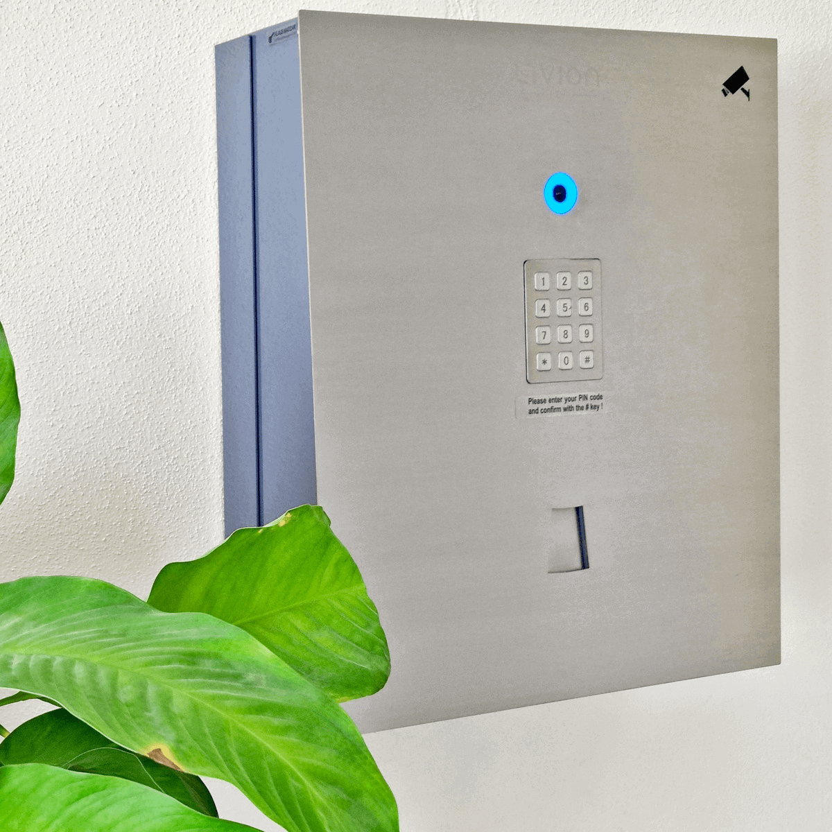 Elektronischer Wandsafe mit PIN-Code-Tastatur und Kamera zur sicheren Aufbewahrung Moderner elektronischer Wandsafe aus Metall mit PIN-Code-Tastatur, Kamera und Pflanzenblatt im Vordergrund